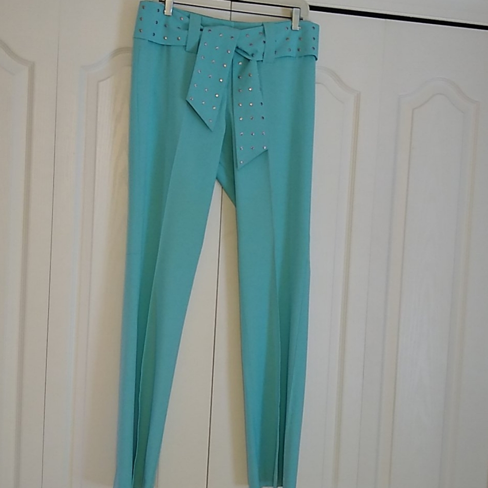 Cache with a rivetive belt turquoise pants.